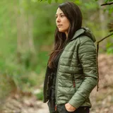 Женщина в куртке цвета Olive на лесной тропе